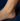 Silver anklet on a person's ankle against a dark background