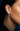 Close-up of an ear wearing a diamond hoop earring with a dark background