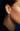 Close-up of an ear wearing a diamond hoop earring with a dark background