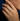 Close-up of a hand wearing a diamond ring against a dark background